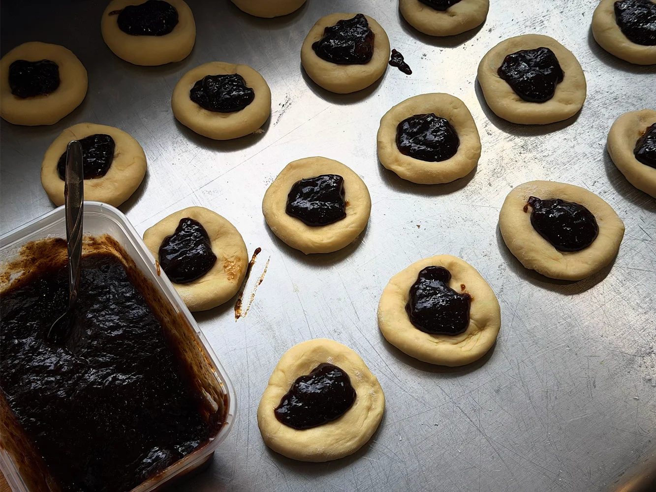 Raw buchty dough piped with dark slivkový lekvár
